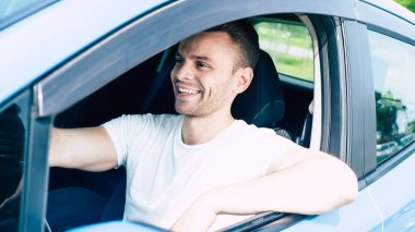 Arabada oturan yakışıklı gülümseyen erkek sürücü