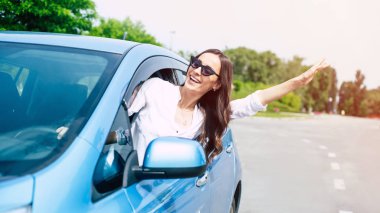 Güneş gözlüğü güzel kadın sürücü araba penceresinden dışarı eğildi