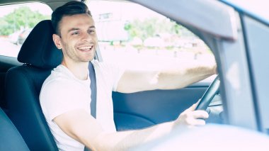 Arabada oturan yakışıklı gülümseyen erkek sürücü