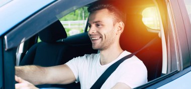 Arabada oturan yakışıklı gülümseyen erkek sürücü