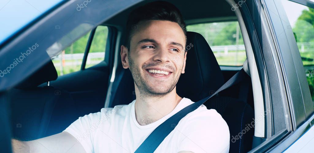 Handsome smiling male driver sitting in car