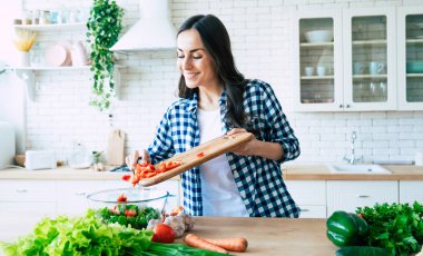 Güzel genç kadın mutfakta sebze salatası hazırlıyor. Sağlıklı Gıda. Vegan Salatası. Diyet. Diyet Kavramı. Sağlıklı yaşam tarzı. Evde yemek pişirmek. Yemek hazırlayın. Masada malzemeleri kesme