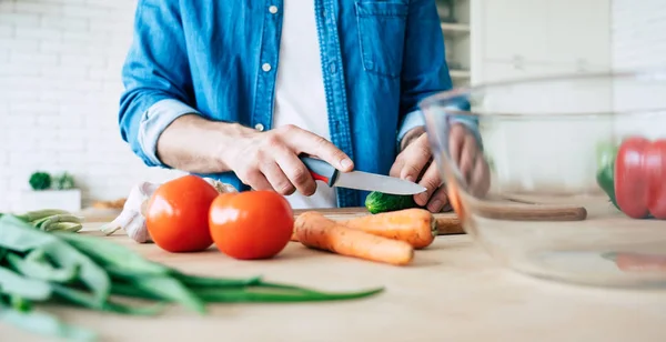 Man cooking healthy food. Fresh vegetables on the cutting board. Concept of cooking. Diet. Healthy and vegan lifestyle. Cooking at home. Prepare food. Male hands cutting vegetables in the kitchen