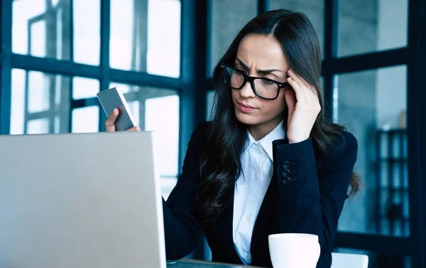 Worried business woman in formal wear is reading a notification from her laptop while sitting at office.