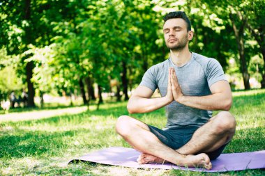 Erkek yoga gevşemesi. Sportif ve ince yakışıklı genç adam şehir parkı açık havada yoga egzersizleri yapıyor. Sağlıklı yaşam tarzı ve güçlü ruh ve beden