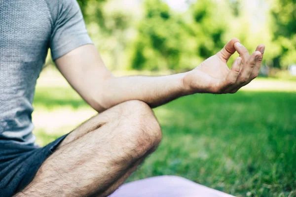 Cropped shot of male yoga relaxation. Sporty and slim handsome young man is doing yoga exercises in city park outdoors. Healthy lifestyle and strong soul and body