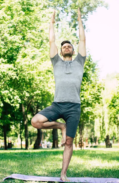 Male yoga relaxation. Sporty and slim handsome young man is doing yoga exercises in city park outdoors. Healthy lifestyle and strong soul and body