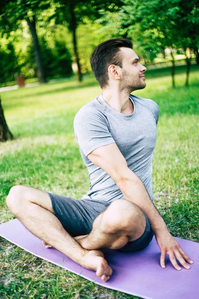 Male yoga relaxation. Sporty and slim handsome young man is doing yoga exercises in city park outdoors. Healthy lifestyle and strong soul and body