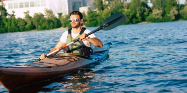 Aktif tatillerin keyfini çıkarın. Kano da kürek çeken aktif adamın arka görünümü