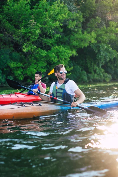 Adventurous friends on kayaks are paddling on the river