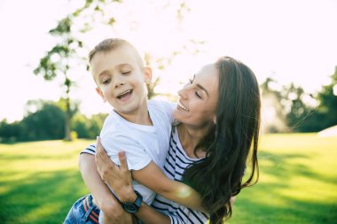 Mutlu bir aile günü. Onu sevimli küçük oğlu ile güzel güzel genç anne parkta açık havada çim üzerinde yatarken eğlenceli ve birbirlerine sarılma