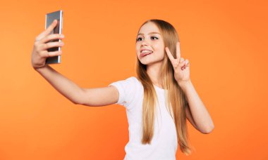 O stüdyoda izole onu akıllı telefonda selfie fotoğrafı yaparken beyaz t-shirt trendy şık güzel sarışın kız yakın çekim