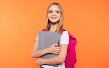 Sırt çantası ile güzel gülümseyen ve mutlu okul kız sarı arka plan üzerinde poz