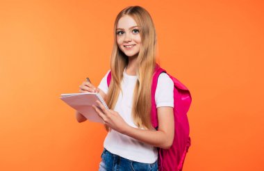 Sırt çantası ile güzel gülümseyen ve mutlu okul kız sarı arka plan üzerinde poz