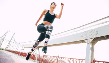 Emin ve konsantre genç kadın köprüde açık havada koşu olduğunu