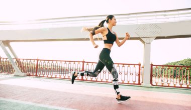 Güçlü vücut iken sağlıklı yaşam. O trendy spor giysileri çalışır zaman güzel sportif kadının yan görünüm tam uzunlukta fotoğraf.