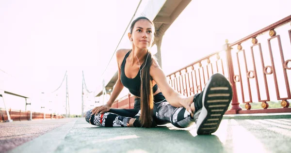 Young confident woman is stretching outdoors. Physical activity in big city