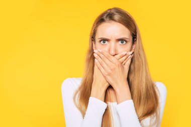 Kelime yok. Sarı üzerinde izole elleri yardımıyla kapalı ağız ile güzel sarışın kadının şok yüzü