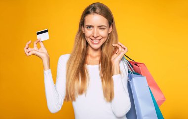 Sarı arka plan üzerinde mutlu müşteri portresi. Satın almalar ellerde. Alışveriş konsepti. Alışveriş poşetleri ile kadın