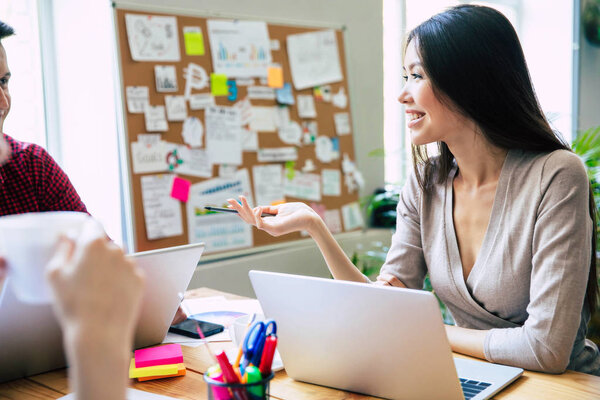 Группа молодых современных сотрудников в элегантной повседневной одежде что-то обсуждают во время работы в креативном офисе. Заводи. Коворкинг пространство. Бизнес идеи
