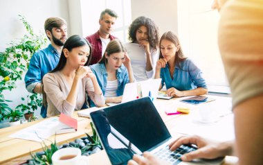 Ofiste veya co-çalışma alanında rahat giysiler içinde Modern mutlu başlangıç ekibi çalışıyor ve onları planları ve fikirleri tartışmak