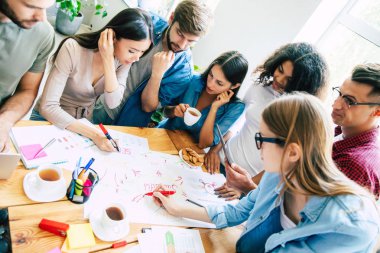 Ofiste veya co-çalışma alanında rahat giysiler içinde Modern mutlu başlangıç ekibi çalışıyor ve onları planları ve fikirleri tartışmak