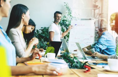 Ofiste veya co-çalışma alanında rahat giysiler içinde Modern mutlu başlangıç ekibi çalışıyor ve onları planları ve fikirleri tartışmak.