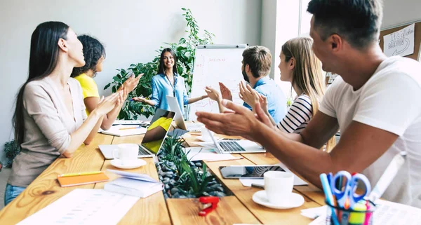Ofiste veya co-çalışma alanında rahat giysiler içinde Modern mutlu başlangıç ekibi çalışıyor ve onları planları ve fikirleri tartışmak.