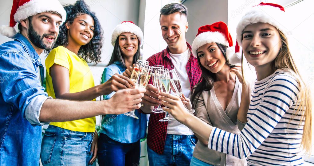 Group of happy multiracial friends celebrating together Christmas with glasses of champagne