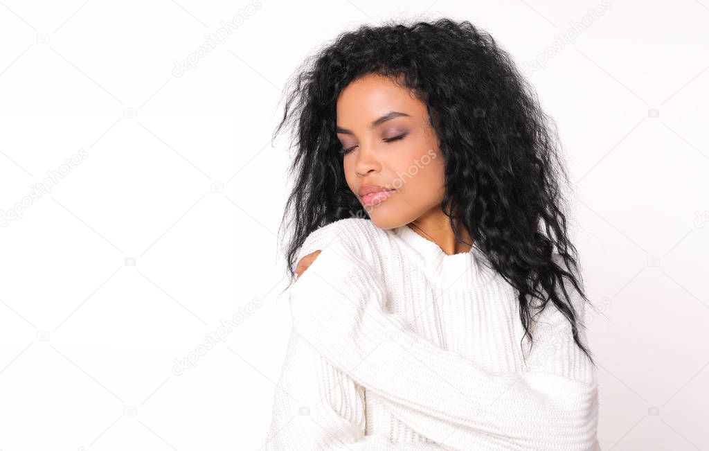 tender beautiful mixed race woman wearing white winter sweater posing with closed eyes on white studio background 