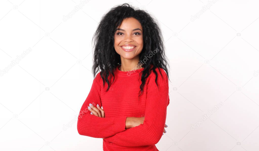 beautiful mixed race woman in warm red sweater standing with crossed arms and looking at camera on white  studio background 