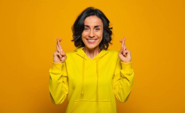 İşe yaradı! Sarı bir kapüşonlu giyinmiş neşeli ve memnun bir kızın yakın plan fotoğrafı, geniş bir gülümseme ve şans diliyor, sonuçtan memnun, ve şans onun yanındaydı..