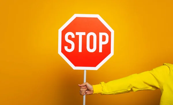 Stop sign. Girl in a yellow hoodie showing only her hand with \