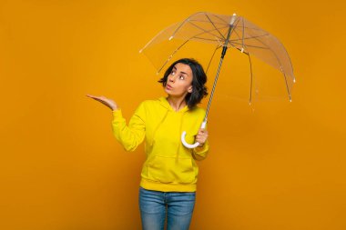 Yağmur nerede? Sarı kapüşonlu, şeffaf şemsiyeli, şaşırmış bir kızın yarım boy fotoğrafı..