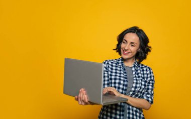 İşimi yapıyorum. Siyah beyaz kareli tişörtlü, gülümseyen bir kızın yarım boy fotoğrafı. Sağ elinde büyük gri defterini tutuyor ve işini yapıyor..