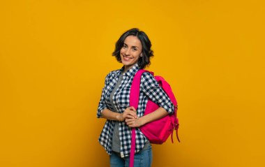  Çok iyi bir öğrenci olacağım! Genç bir öğrencinin yarım boy fotoğrafı, gelişigüzel giyinmiş, kameraya geniş bir şekilde gülümsüyor, sevimli pembe sırt çantasını bir omzunda tutuyor, günüyle tanışmaya hazır..