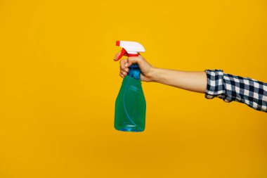 Bir sprey şişesi. Yeşil sprey bir şişenin yakın plan fotoğrafı beyaz sprey ve kırmızı tetik, bir kızın elinde, sarı arka planda..