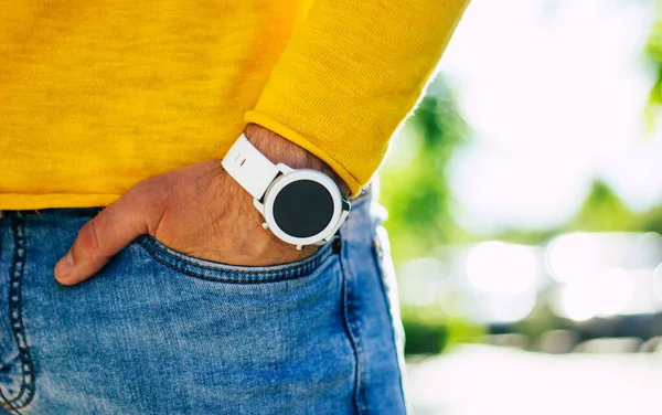 Up-to-date smartwatch. A close-up photo of a white, stylish up-to-date swartwatch, with round screen, on a young man\'s hand.