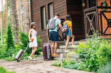 Otelin yakınında. Seyahat eden, bavulları ve sırt çantaları olan bir aile fotoğrafı. Anne ve baba aşağıya bakıyor..