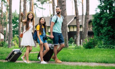 Ailesi ormandaki otelde kalıyor. Ormandaki otellerine giden yolda yürüyen genç bir ailenin tam boy fotoğrafı. Bu arada annesi oteli eliyle işaret ediyor.. 