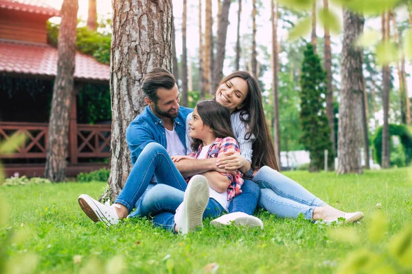 Mooi Gelukkig Gezin Terwijl Samen Zitten Het Gras Knuffelen Elkaar — Stockfoto