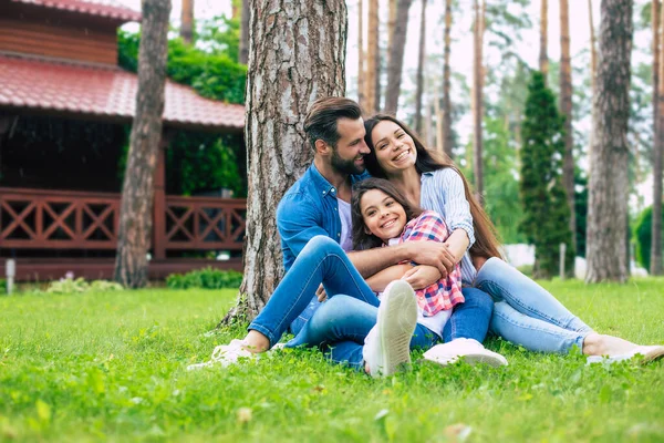 Mooi Gelukkig Gezin Terwijl Samen Zitten Het Gras Knuffelen Elkaar — Stockfoto