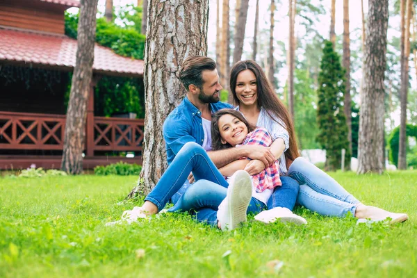 Mooi Gelukkig Gezin Terwijl Samen Zitten Het Gras Knuffelen Elkaar — Stockfoto