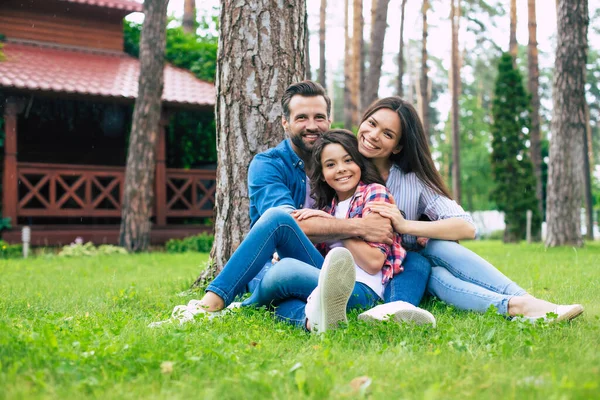 Mooi Gelukkig Gezin Terwijl Samen Zitten Het Gras Knuffelen Elkaar — Stockfoto