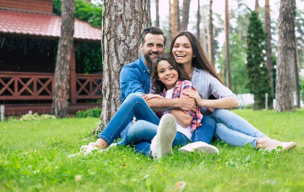 Mooi Gelukkig Gezin Terwijl Samen Zitten Het Gras Knuffelen Elkaar — Stockfoto