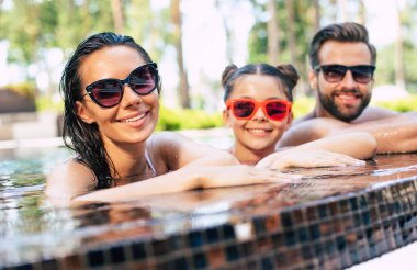 Yakışıklı, gülümseyen bir adam ve tatlı, heyecanlı bir kadın. Küçük tatlı kızlarıyla birlikte yazın havuzda eğleniyorlar. Otelde dinlenirken..