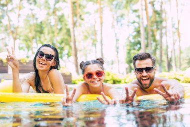 Yakışıklı, gülümseyen bir adam ve tatlı, heyecanlı bir kadın. Küçük tatlı kızlarıyla birlikte yazın havuzda eğleniyorlar. Otelde dinlenirken..