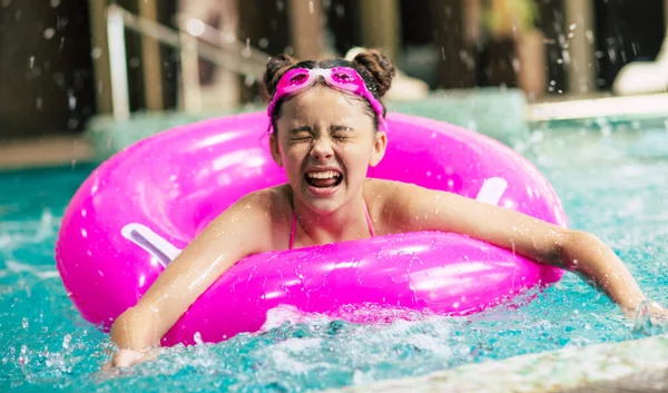 在一个炎热的夏天 穿着护目镜 戴着粉色充气环在游泳池里玩耍的快乐小女孩 孩子们学习游泳 孩子们的玩具 家庭海滩度假 — 图库照片