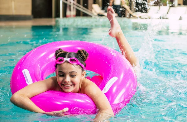 在一个炎热的夏天 穿着护目镜 戴着粉色充气环在游泳池里玩耍的快乐小女孩 孩子们学习游泳 孩子们的玩具 家庭海滩度假 — 图库照片