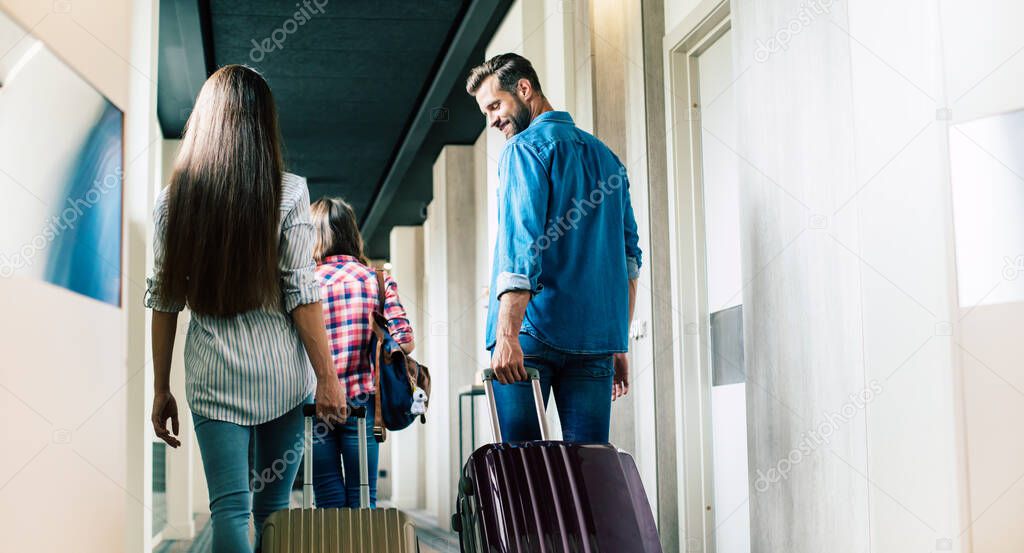 Beautiful happy excited family with a backpack and suitcases in modern hotel